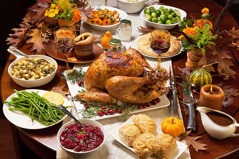 Horizontal image of a large Thanksgiving table with assorted food.