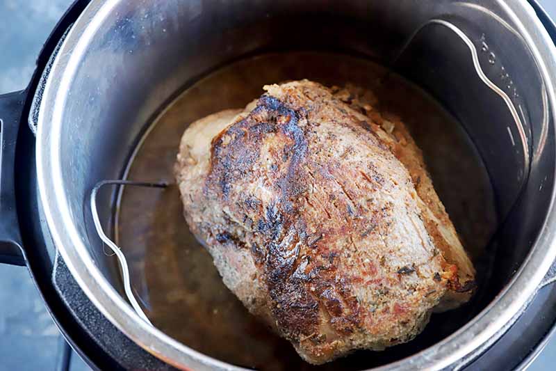 Horizontal image of a large piece of meat scorched in an instant pot.