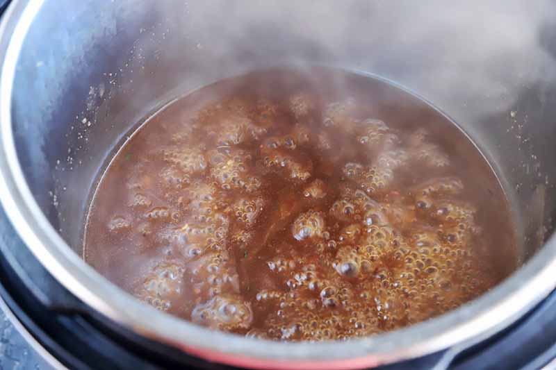 Horizontal image of gravy boiling in a pot.