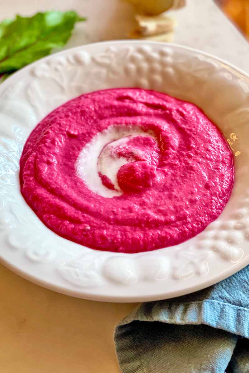 Vertical image of a white dish filled with a bright pink dip with a dollop of white spread, with text on the top and bottom of the image.