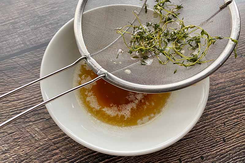 Horizontal image of straining herbs from a brown butter.