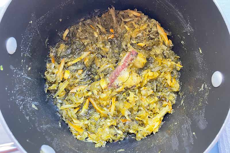 Horizontal image of a concentrated chunky mixture of shredded squash and rinds in a pot.