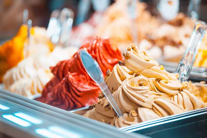 Horizontal image of trays of gelato piled high with scoops.