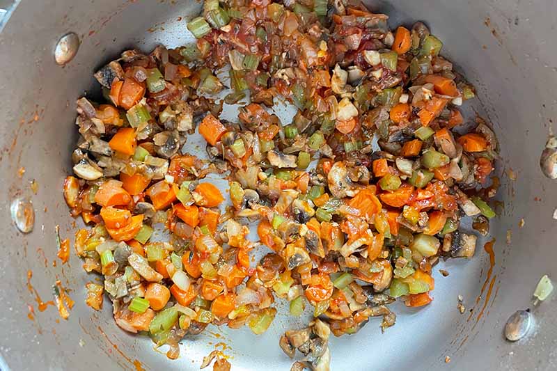 Horizontal image of cooking chopped assorted vegetables in a pot.