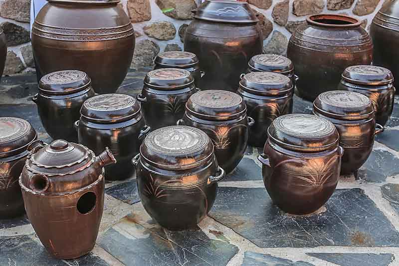 Horizontal image of multiple big brown fermenting jars.