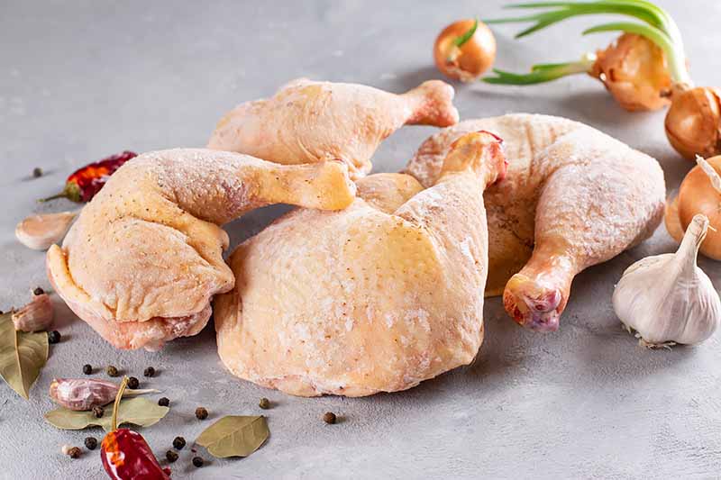 Horizontal image of frozen poultry legs next to assorted ingredients.