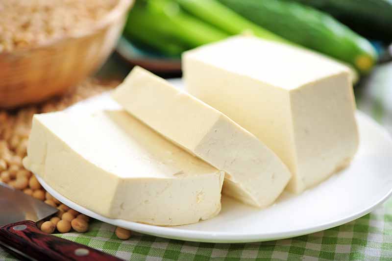 Horizontal image of slices of white soy product on a white plate.