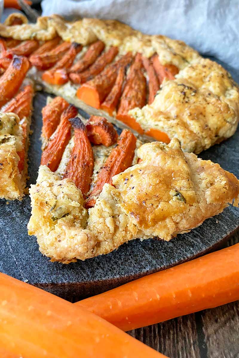 Vertical image of a slice of a savory pasty topped with carrots.