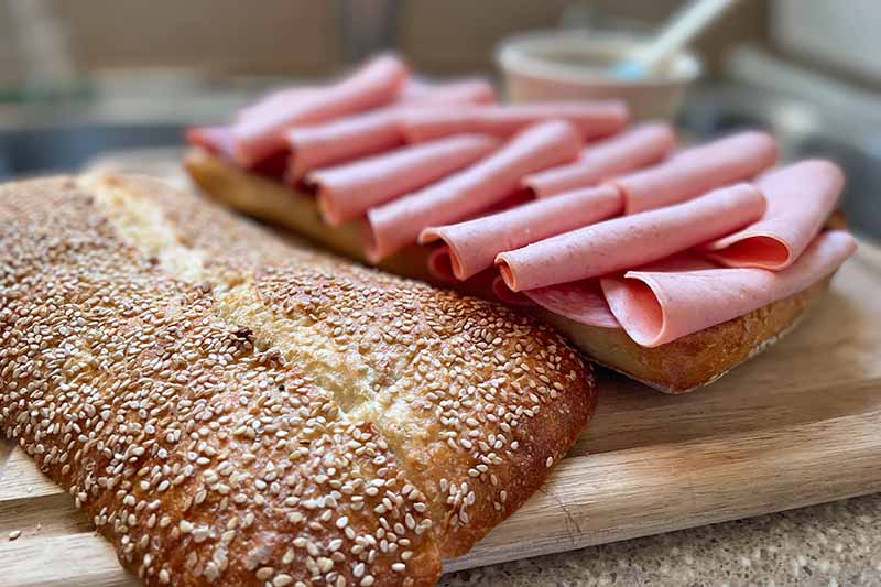 Horizontal image of folded cold cuts on bread on a cutting board.