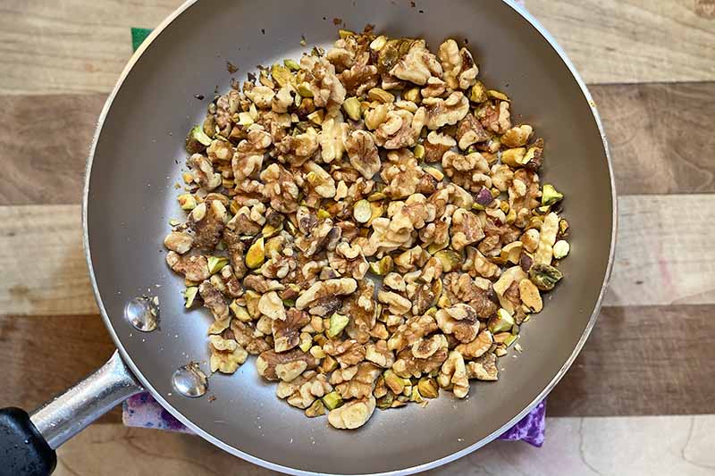 Horizontal image of toasted nuts and coconut in a pan.