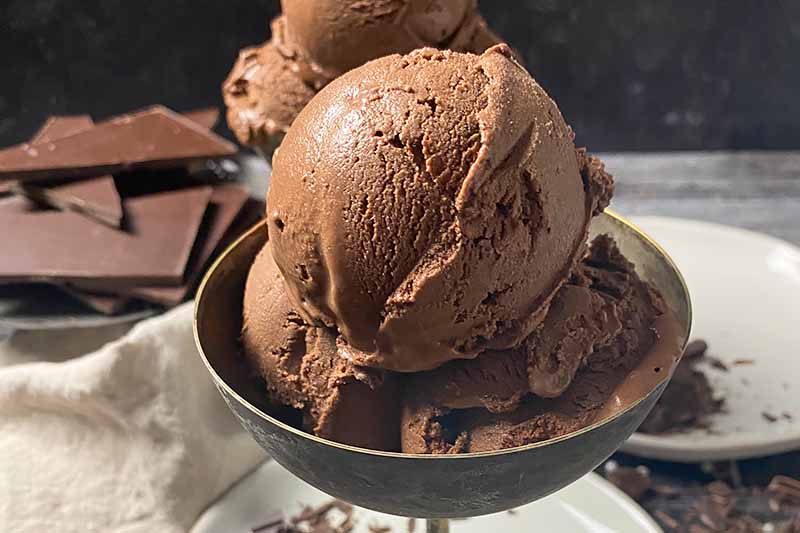 Horizontal image of a small metal goblet filled with scoops of dark brown ice cream.