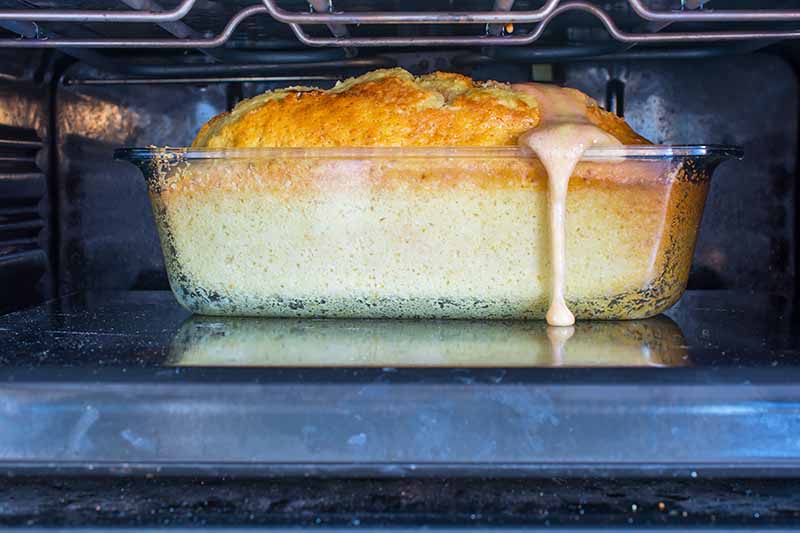 Horizontal image of a cake that overflowed from the pan in the oven.
