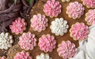 Horizontal top-down image of assorted pink and white decorated baked goods on a wooden surface.