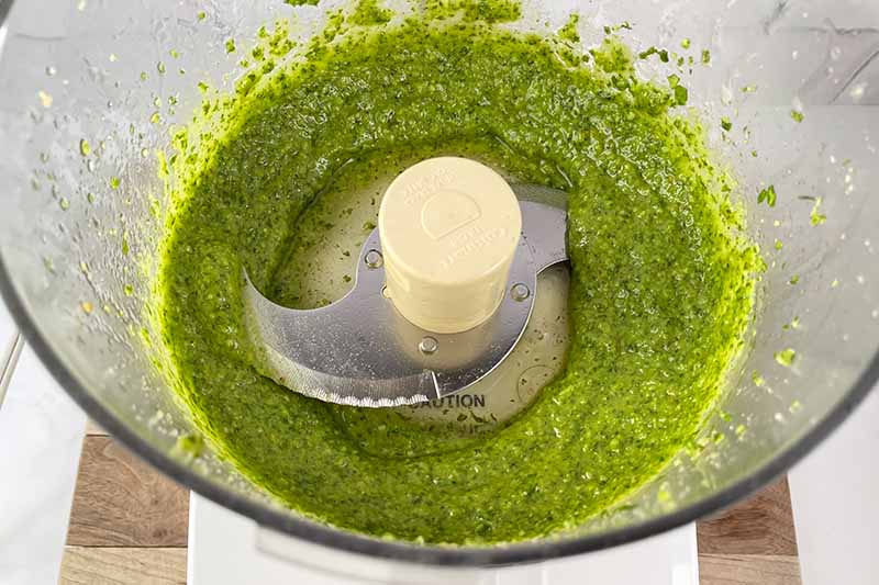 Horizontal image of a thick green spread in a food processor.