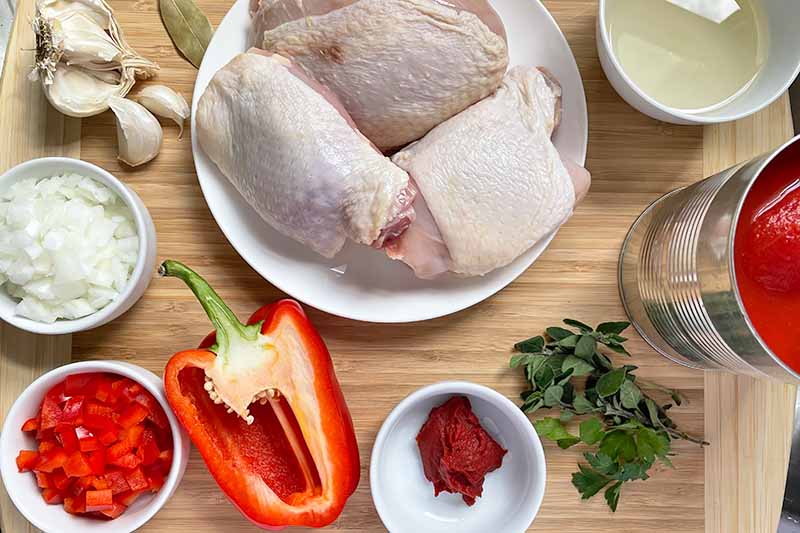 Horizontal image of raw poultry on a plate surrounded by other prepped ingredients.
