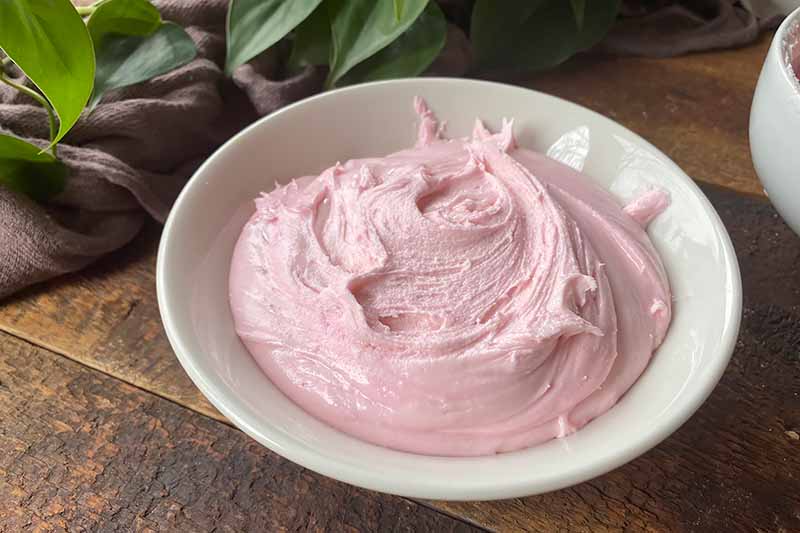 Horizontal image of pink frosting in a white bowl.