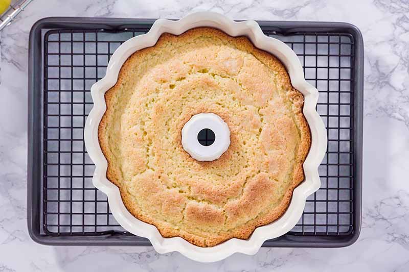 Horizontal image of a cake in a bundt pan on a cooling rack.