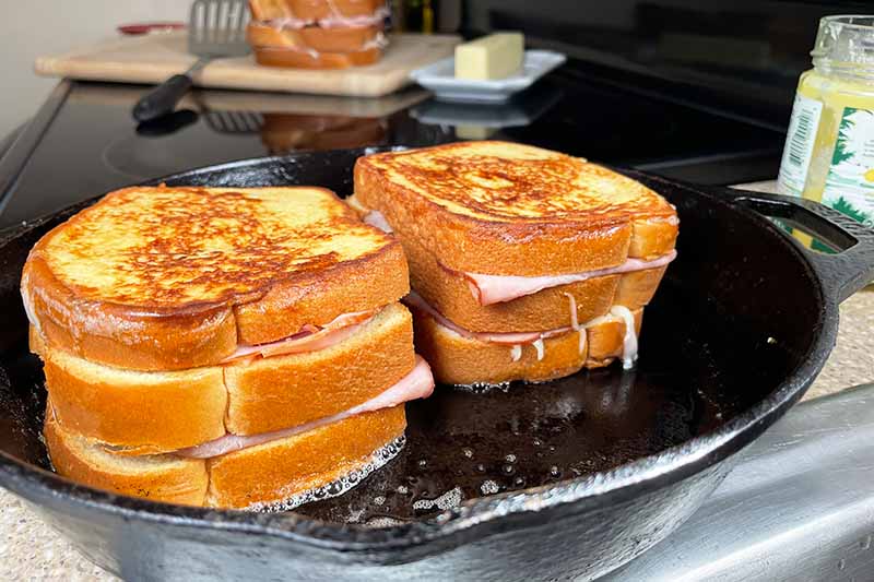 Horizontal image of two large sandwiches toasted in a cast iron pan.