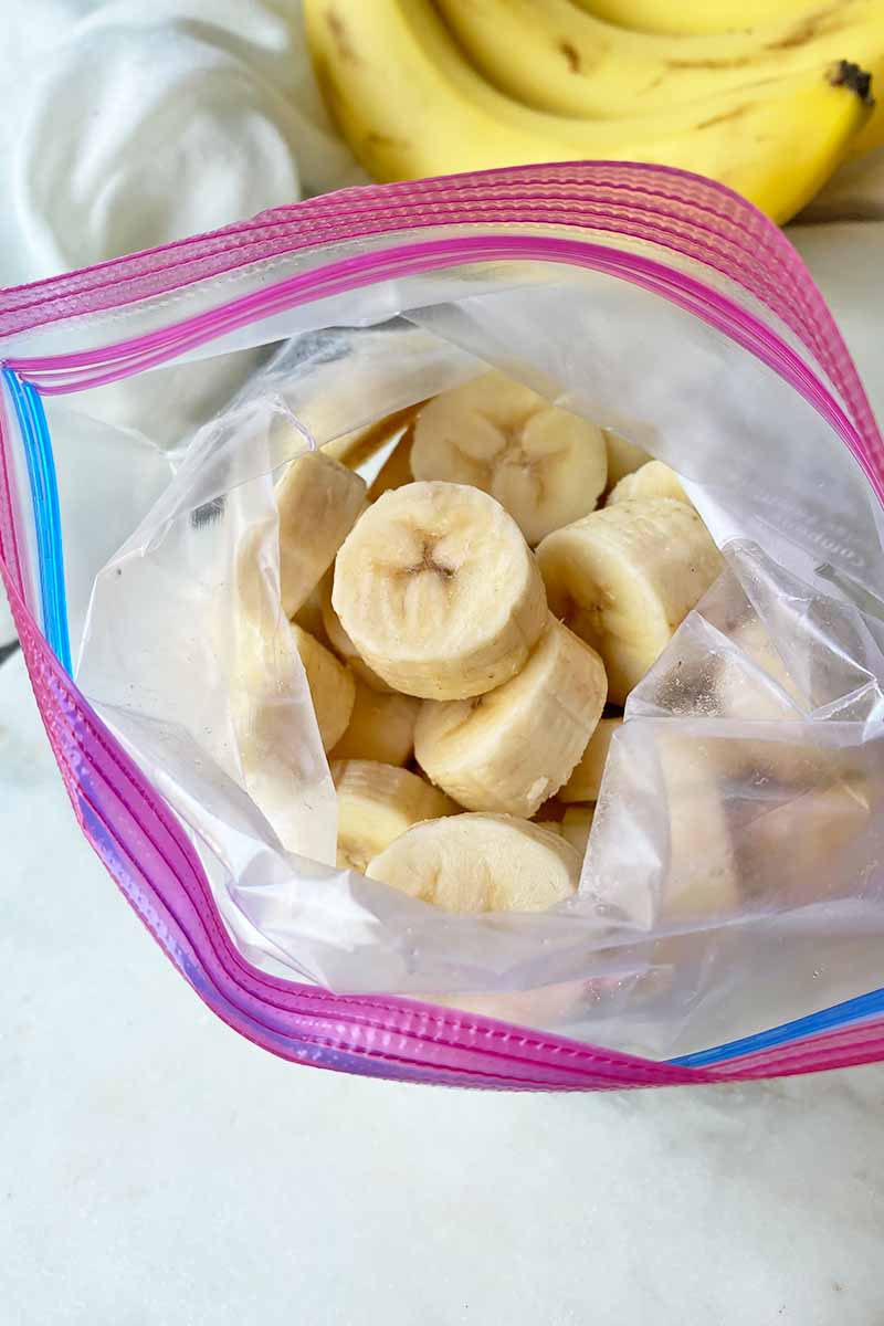 Vertical image of slices of fresh fruit inside an airtight plastic bag.