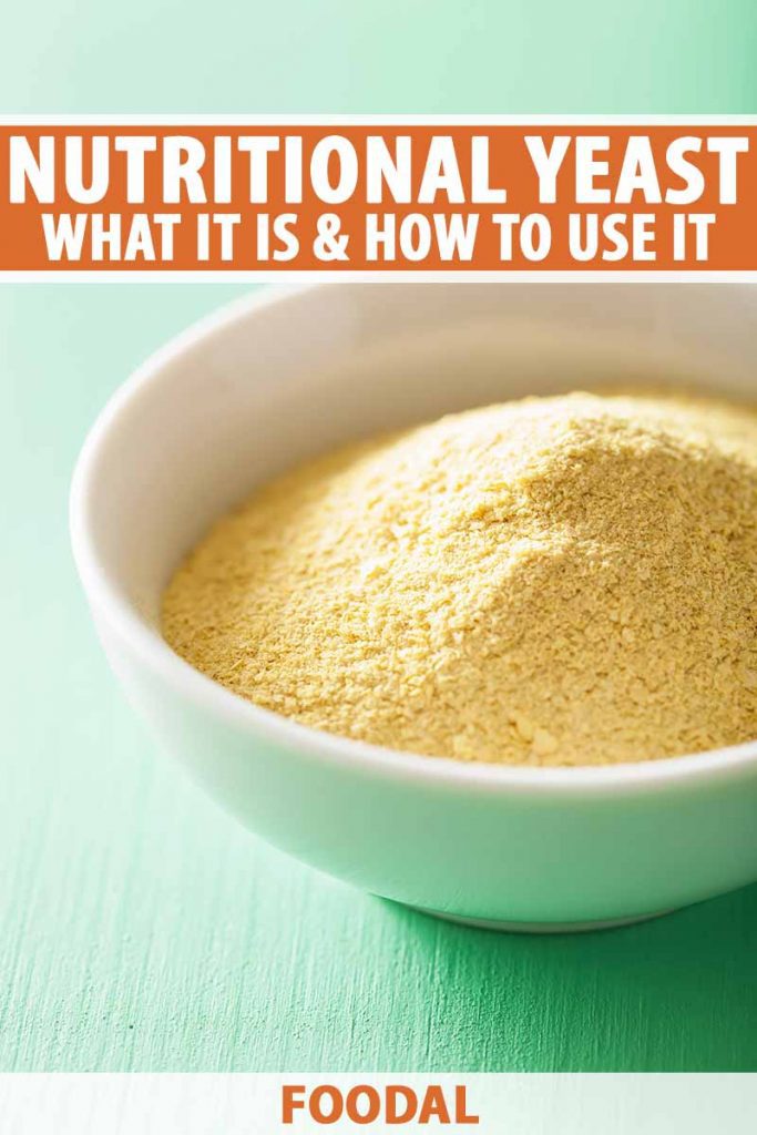 Vertical image of a bowl of nutritional yeast on top of a teal wooden surface, with text on the top and bottom of the image.