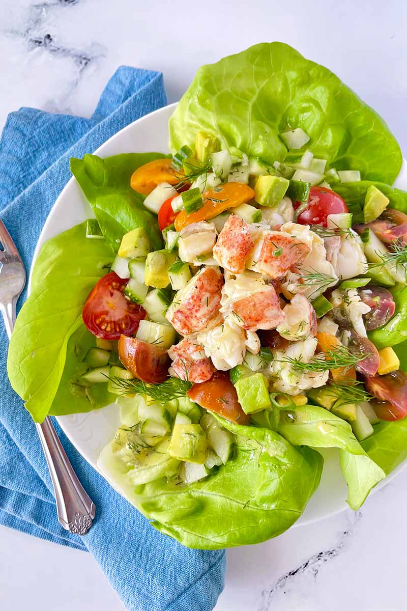 Vertical image of a seafood salad on bib lettuce on a blue napkin.
