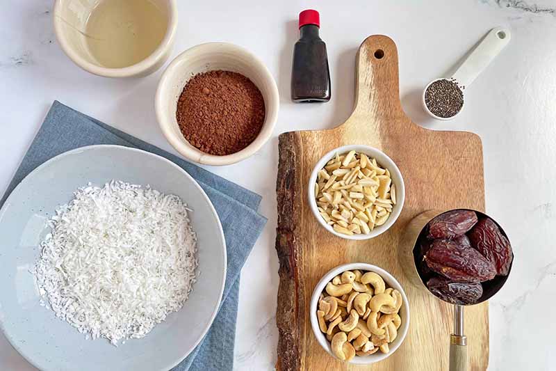 Horizontal image of prepped and measured ingredients in assorted bowls and spoons, some on a wooden cutting board.