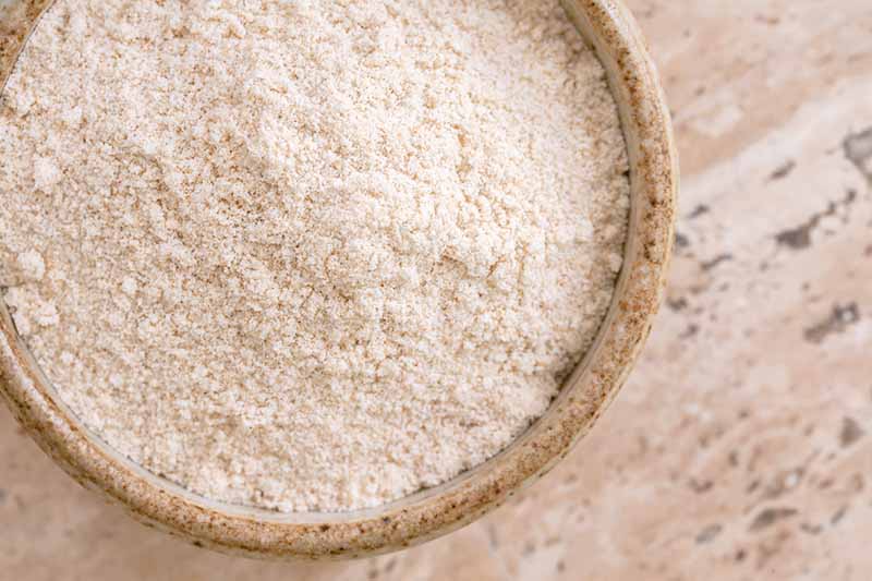 Horizontal image of white flour in a wooden bowl.