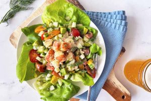 Horizontal image of a white plate with bib lettuce and a seafood and vegetable mixture on a blue napkin.