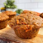 Horizontal image of carrot muffins on a wooden cutting board.