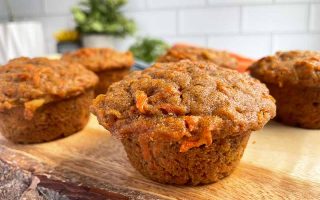 Horizontal image of carrot muffins on a wooden cutting board.