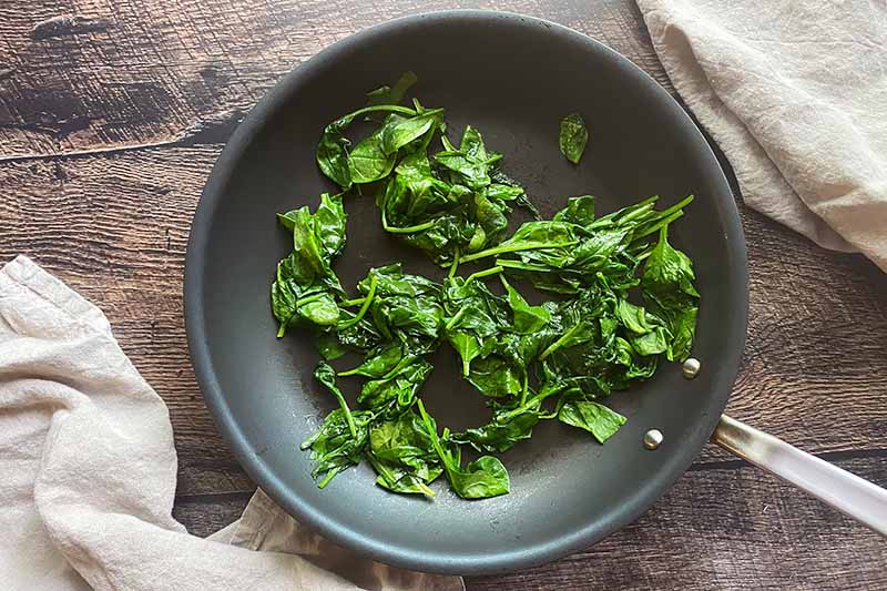 Horizontal image of cooking spinach in a pan.