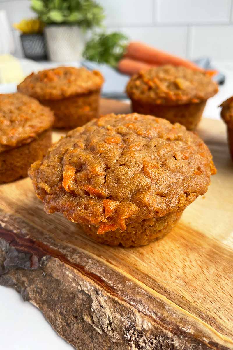Vertical image of large muffins on a wooden board.