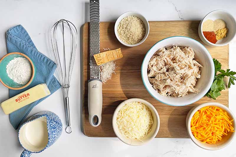 Horizontal image of prepped ingredients and tools on a wooden cutting board.