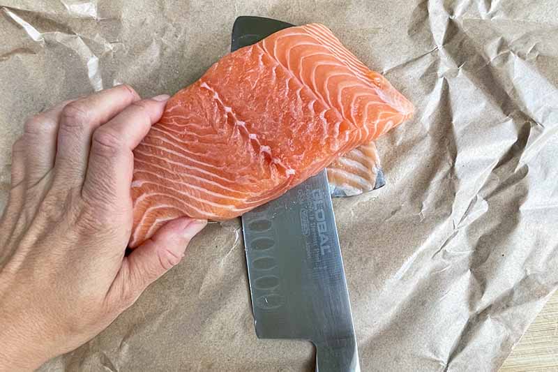 Horizontal image of removing skin from a salmon fillet.