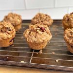 Horizontal image of two rows of streusel-topped muffins on a cooling rack on a baking pan.
