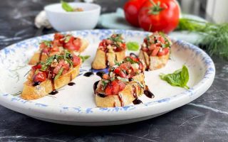 Horizontal image of a platter with bruschetta drizzled with a dark glaze.