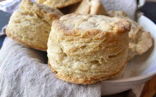 Horizontal image of biscuits in a bowl with a tan towel lining the bowl.