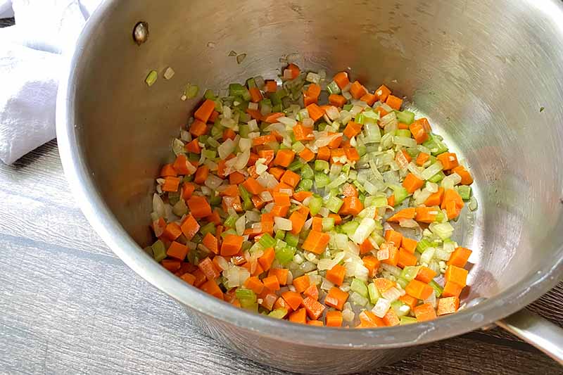 Horizontal image of cooking diced mixed vegetables in a large pot.