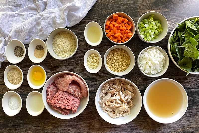 Horizontal image of assorted white bowls with a medley of various measured and prepped ingredients.