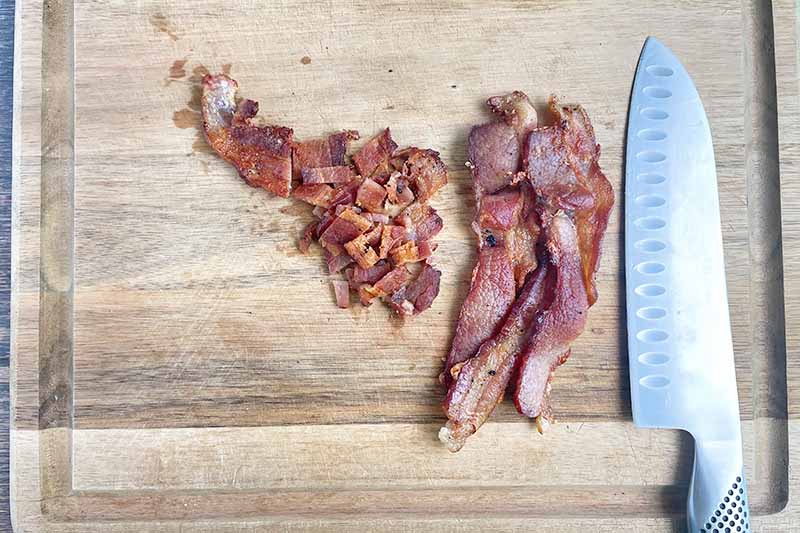 Horizontal image of chopping bacon on a wooden cutting board.