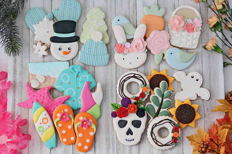 Horizontal image of assorted decorated cookies on a white wooden surface.