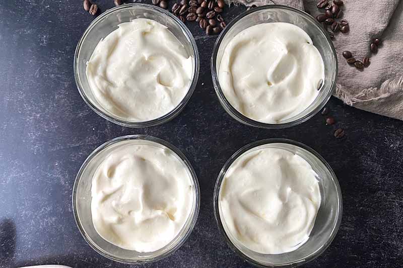 Horizontal image of a layer of whipped cream in four glass bowls.