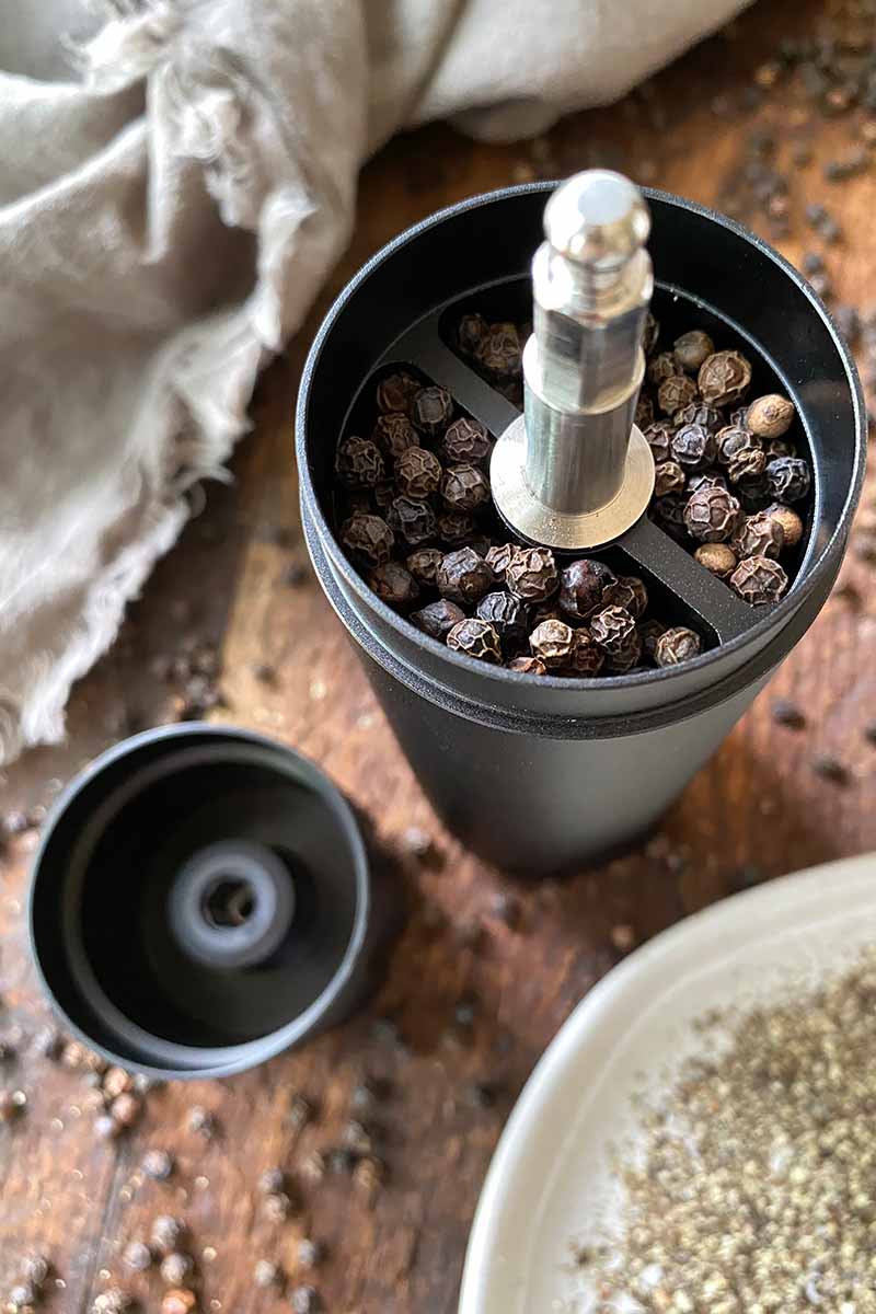 Vertical image of a filled mill with whole peppercorns.