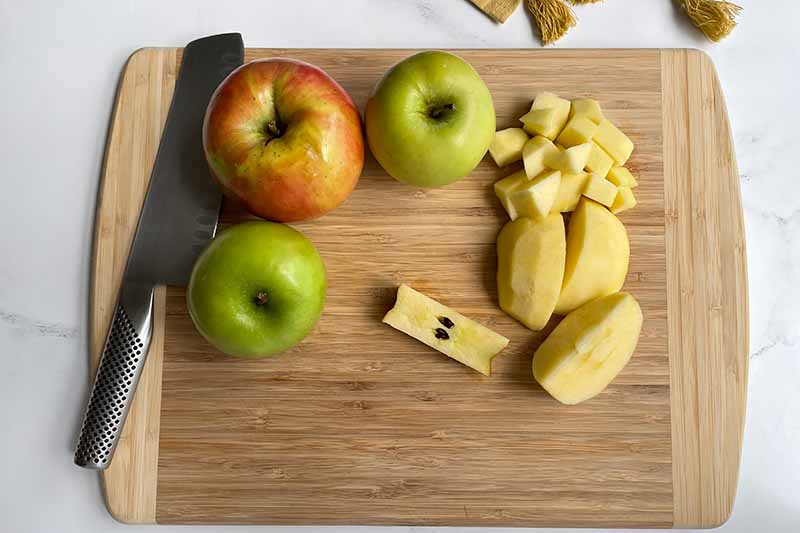 Horizontal image of prepping apples in a wooden cutting board.