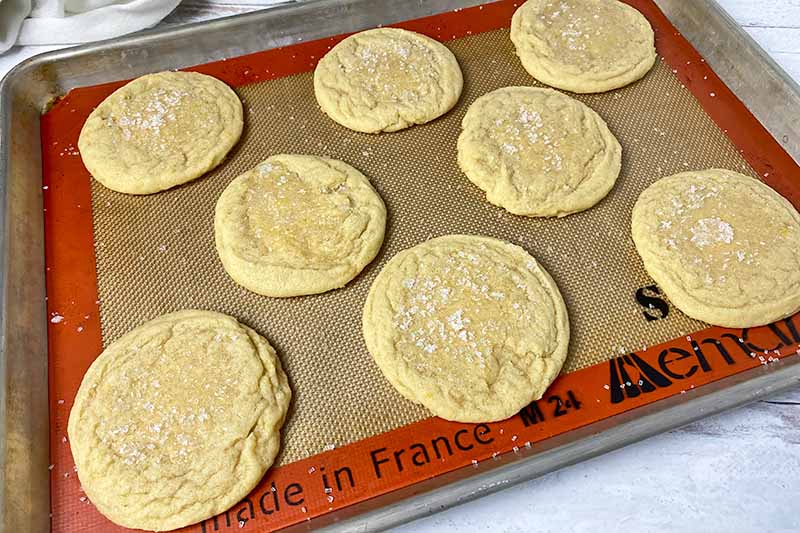Horizontal image of baked portions of dough on a baking sheet lined with a silicone mat.