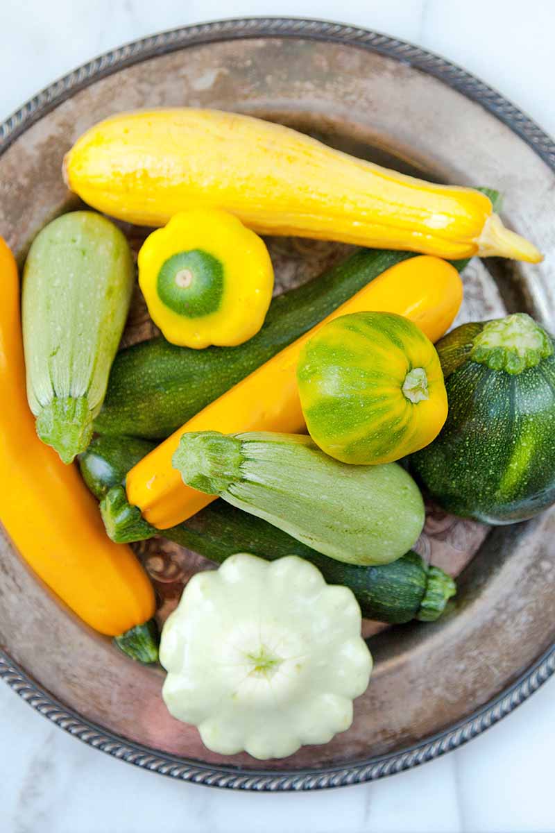 Vertical top-down image of assorted fresh vegetables in a large bowl.