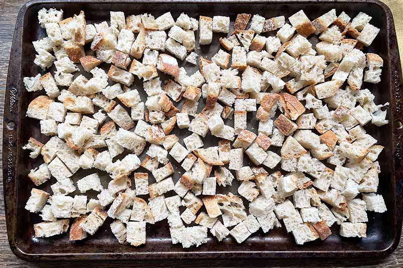 Horizontal image of drying bread cubes on a sheet pan.