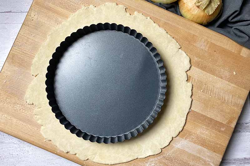 Horizontal image of a flat disc of dough underneath an empty pan.