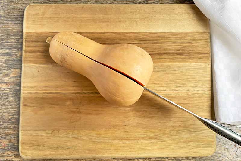 Horizontal image of cutting into a large vegetable on a wooden board.