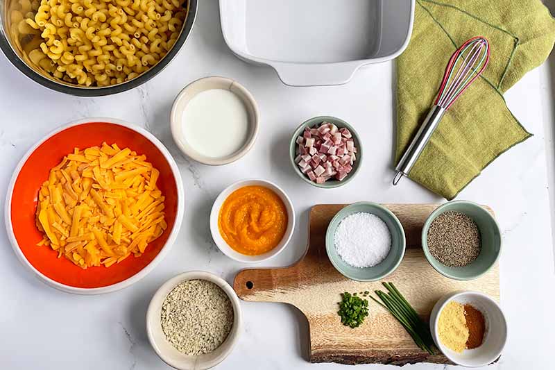 Horizontal image of assorted prepped and measured ingredients in bowls next to a green towel and empty ceramic dish.
